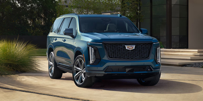 A blue Cadillac SUV parked in a driveway.
