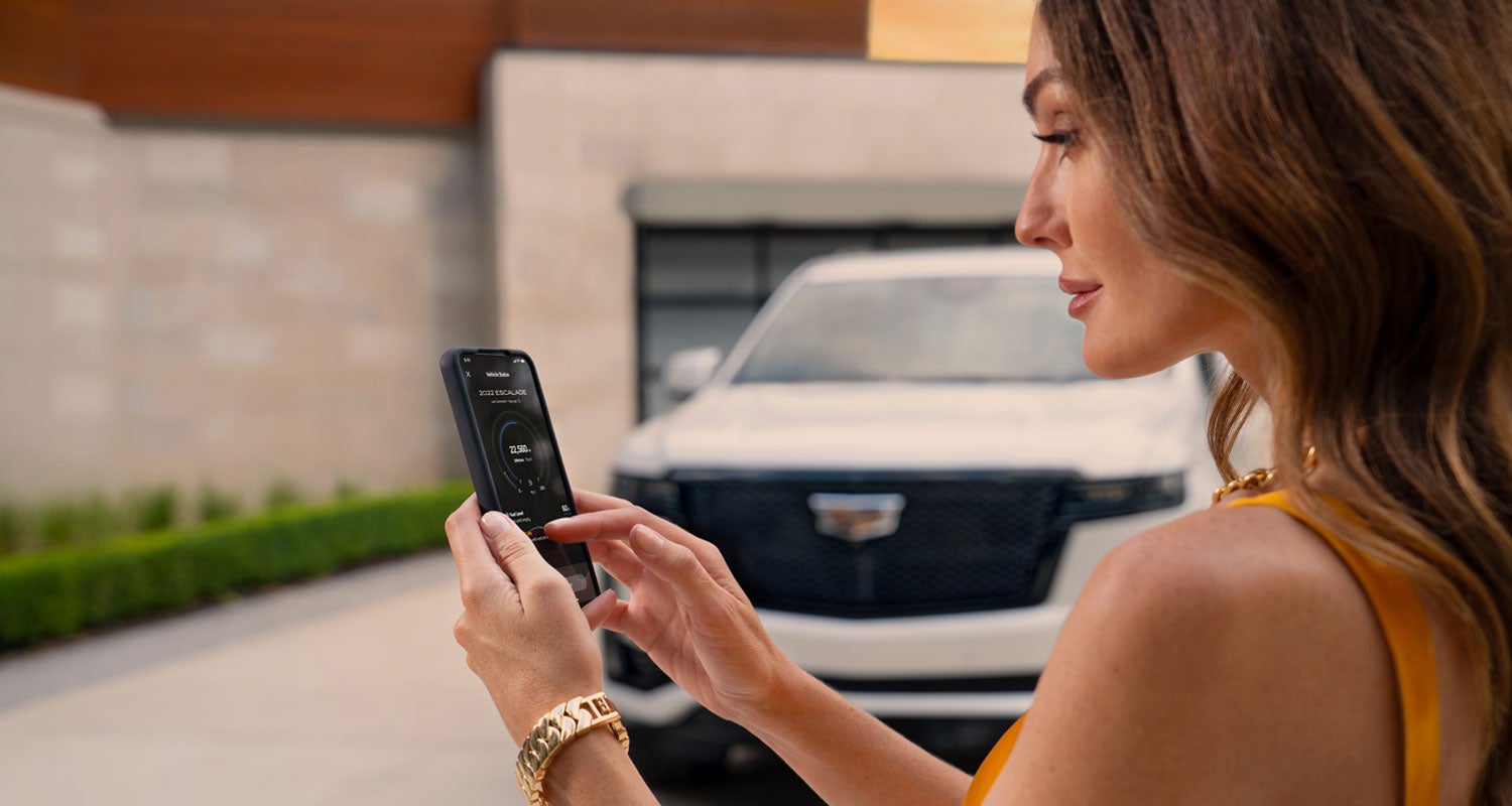 lady checking her mobile with a Cadillac vehicle background | Hudson Cadillac in Poughkeepsie NY