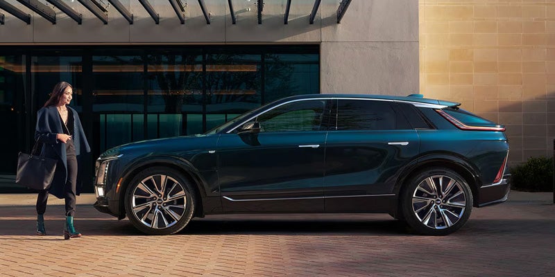 Woman walking toward 2026 Cadillac LYRIQ outside an office